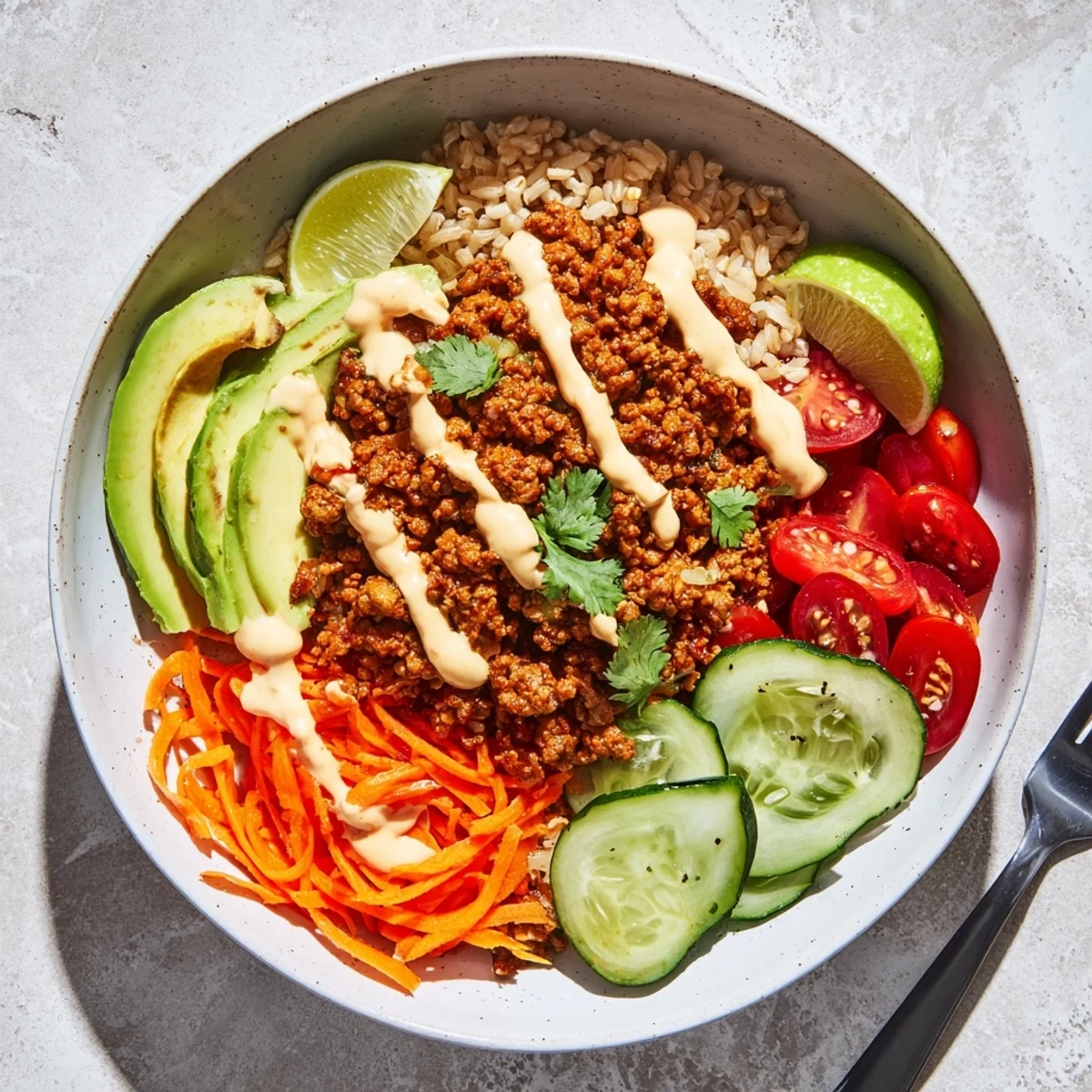 A colorful Plant-Based Meat Bowl topped with fresh veggies and spicy mayo sauce.  