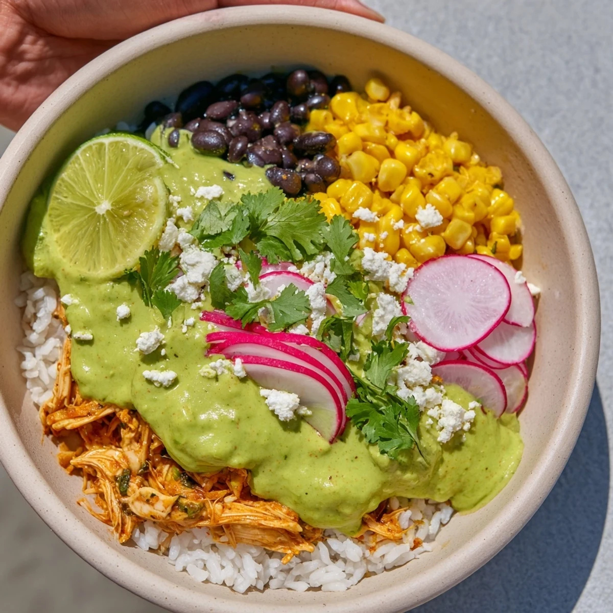 A delicious Green Enchiladas Rice Bowl overflowing with chicken, fresh toppings, and zesty flavors, ready to enjoy.