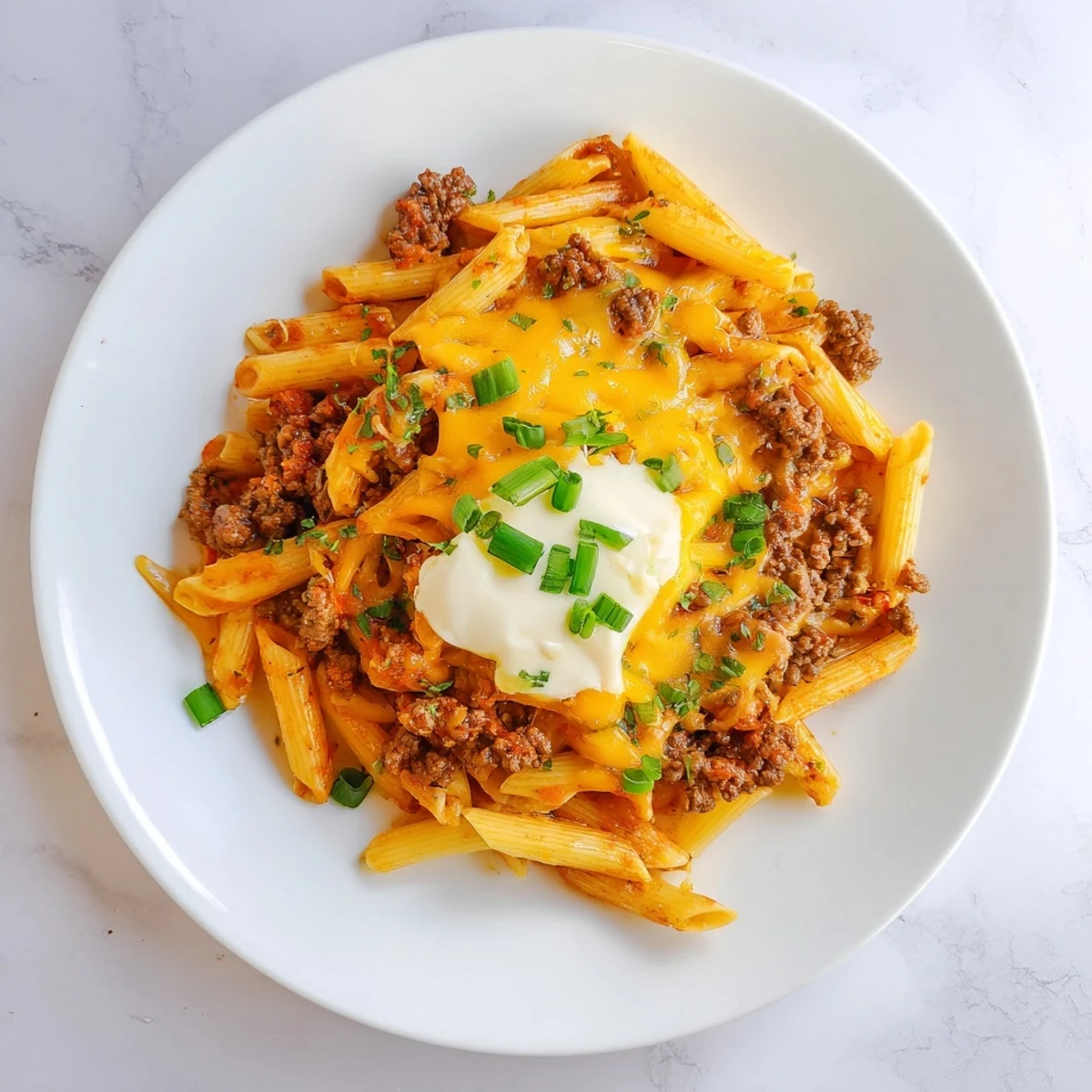 Creamy, cheesy easy beef enchilada pasta: tender pasta, rich sauce, and bubbling cheddar cheese.