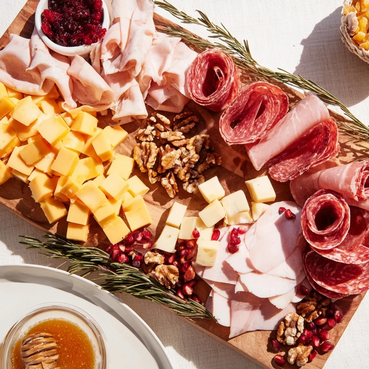 Winter Forest Meat and Cheese Charcuterie Scene with rosemary sprigs and vibrant pomegranate seeds.
