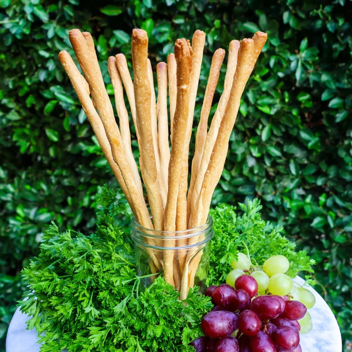 Appetizing "Vertical Forest" appetizer: breadsticks stand tall amidst parsley and colorful grapes.