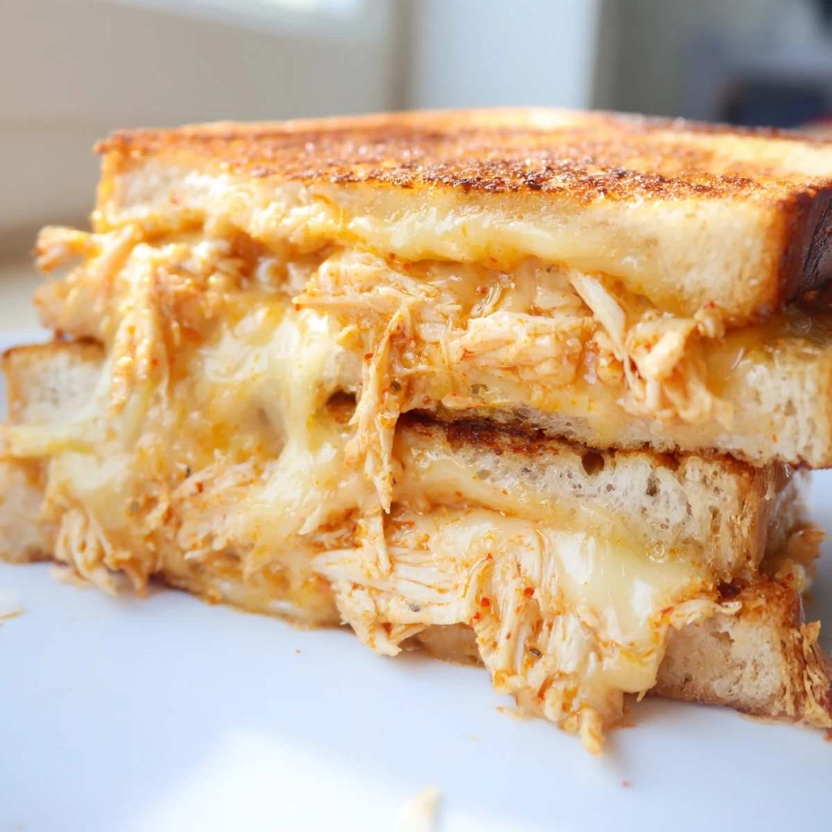 Golden-brown Chili Crisp Honey Chicken Grilled Cheese, dripping with melted cheese, a comforting bite.