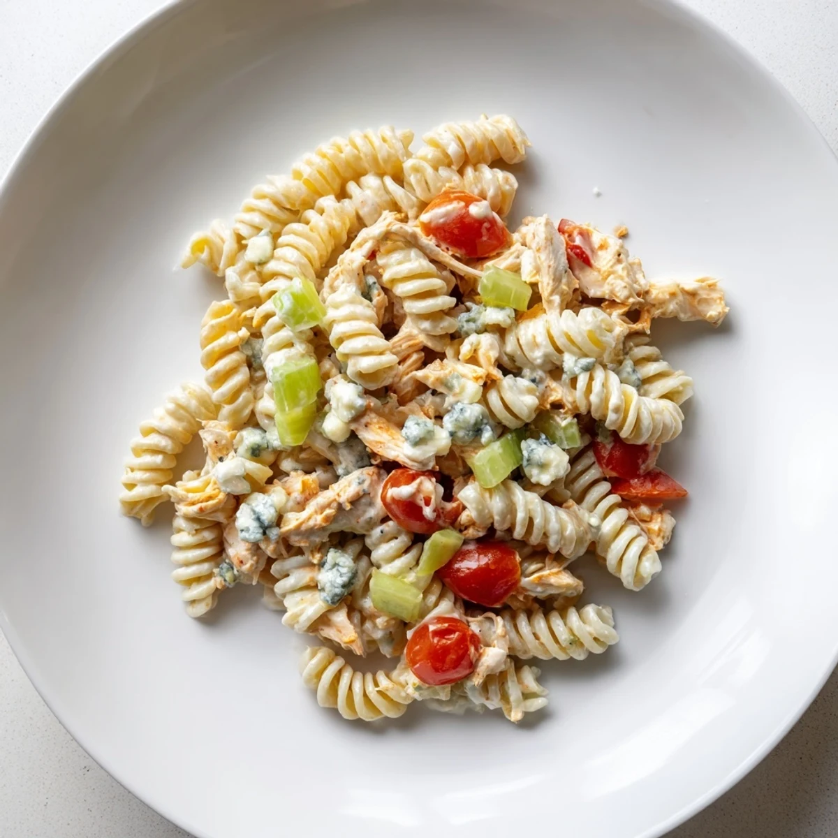 A picnic-ready Buffalo Chicken Pasta Salad served cold, featuring buffalo-coated chicken, red onion, and a refreshing lemon-ranch drizzle.