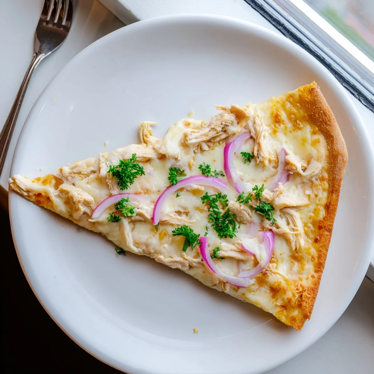 Freshly baked Chicken Alfredo Pizza topped with tender chicken, Parmesan, and chopped parsley garnish.