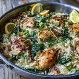 Golden seared chicken thighs and creamy orzo pasta simmer in a bright lemon garlic sauce, garnished with fresh spinach and parsley. 