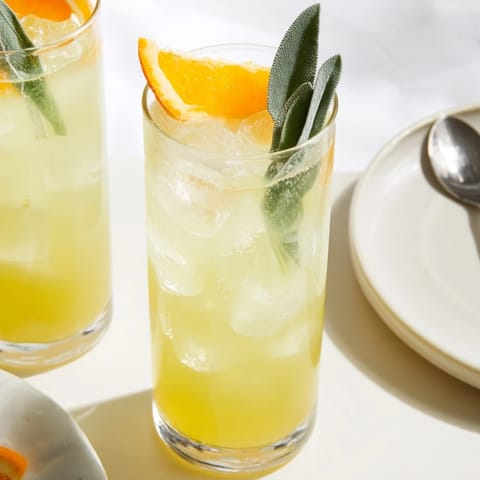 Herbaceous Sage-Fizz Mocktail with citrus slices, bubbly sparkling water, and fresh sage leaves.  