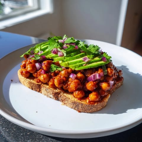 Golden, crispy toast topped with saucy BBQ Chickpeas, garnished with fresh herbs, ready to eat.