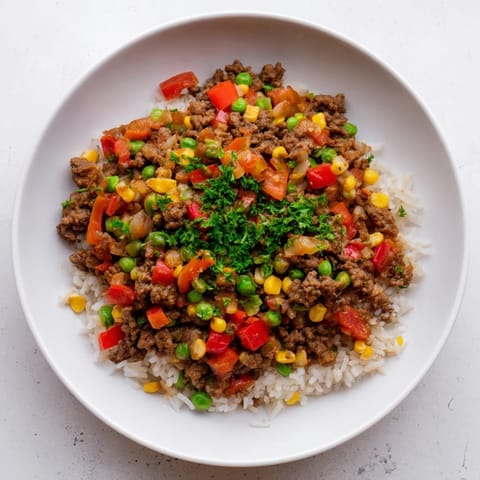 This Ground Beef Skillet with Veggies & Rice is steaming hot, ready to serve with fresh herbs.