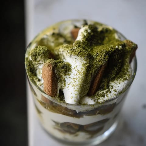 A close-up of Matcha Mascarpone Tiramisu Snow Cups, showcasing creamy layers dusted with matcha snow.