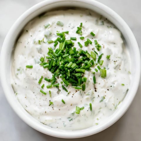 A close-up shot of the fresh Veggie Ranch Dip, ready to be scooped with colorful raw vegetables.