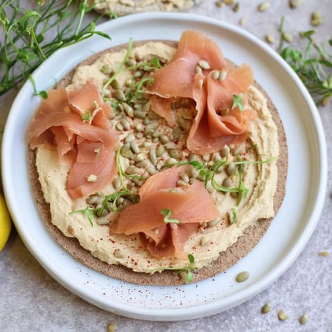 A close-up of The Driftwood Beach appetizer showing delicate fish and sandy hummus ready to serve.