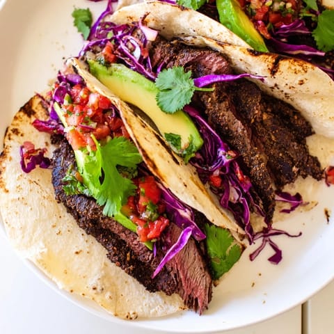 These flavorful Coffee-Rubbed Steak Tacos feature tender steak, colorful toppings, and fresh cilantro sprigs.