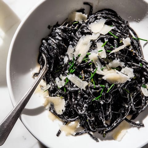 Silky cream sauce clings to dark squid ink pasta, with fresh chives and grated Parmigiano-Reggiano for a restaurant-quality dinner.
