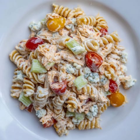 Chilled Buffalo Chicken Pasta Salad tossed with ranch dressing, crisp bell peppers, and cherry tomatoes in a colorful rotini pasta.