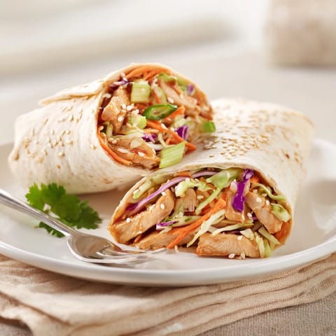 Savory Teriyaki Chicken Wrap stuffed with tender chicken, crisp veggies, and sesame seeds, cut on a wooden board for serving.  