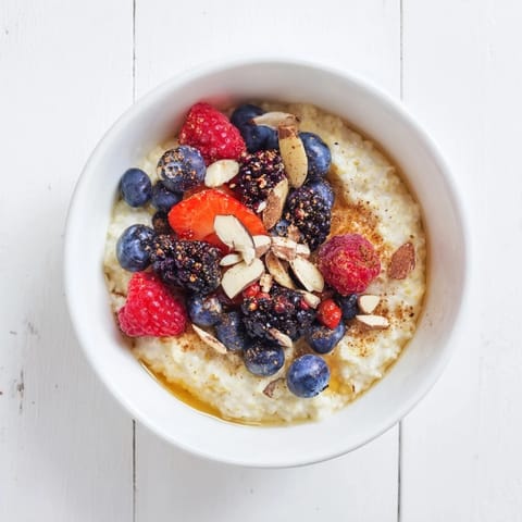 Hearty gluten-free millet porridge, topped with fresh berries, chia seeds, and chopped nuts for a wholesome, energizing meal.