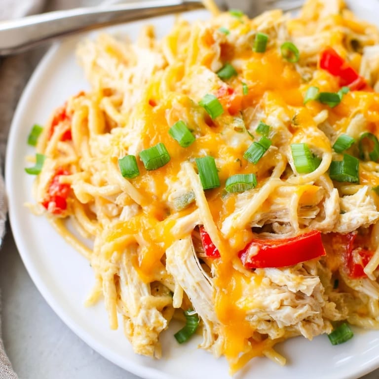 Cheesy layers of Spicy Southern Cheesy Chicken Spaghetti Casserole topped with green onions.