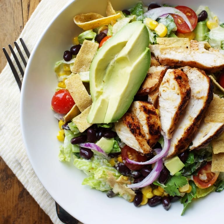 A vibrant serving of Honey Lime Chicken Taco Salad, garnished with fresh cilantro and drizzled with a tangy honey-lime dressing.