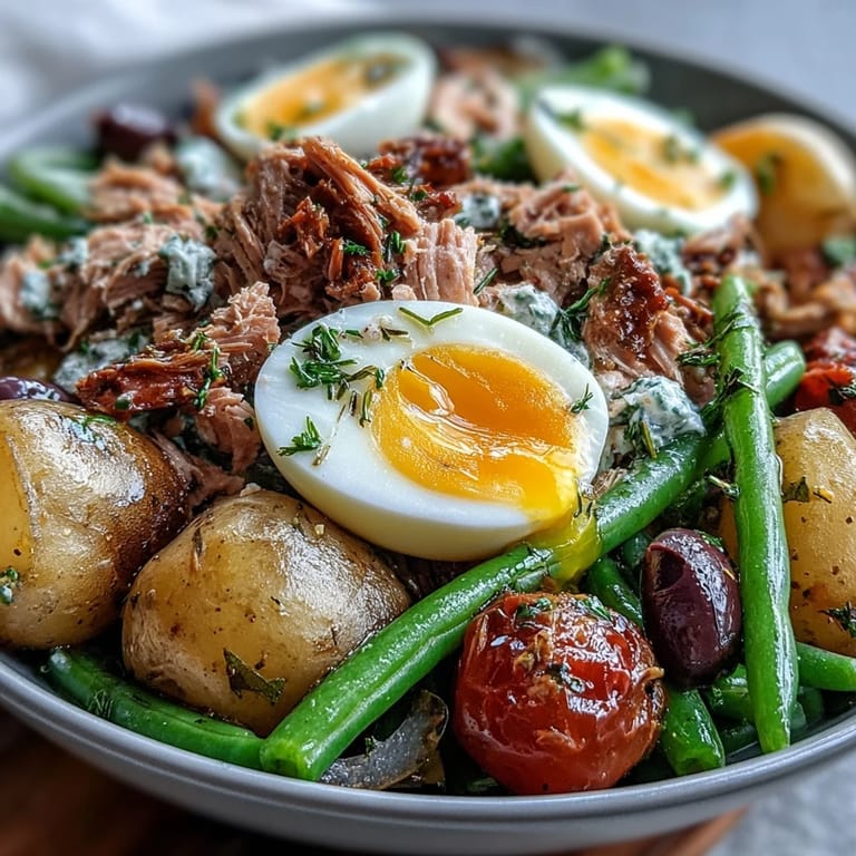 Colorful Spring Niçoise Salad featuring cherry tomatoes, green beans, and olives drizzled with zesty Dijon vinaigrette.