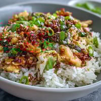 Crispy chili crisp egg fried rice with fluffy scrambled eggs and scallions in a hot wok.