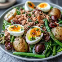 Spring Niçoise Salad with tender tuna, soft-boiled eggs, and vibrant vegetables on a bed of greens.